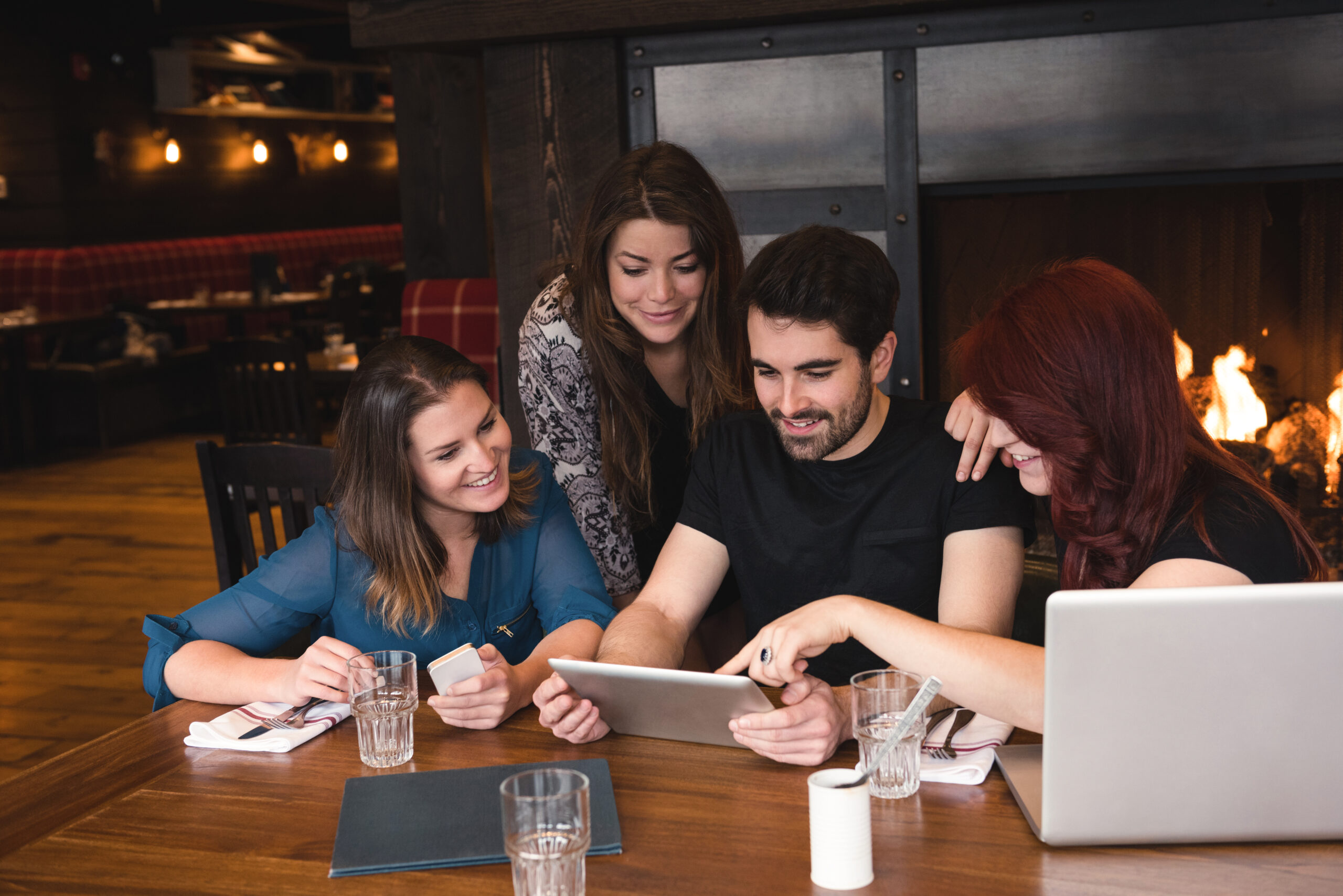 Friends sitting at table and using digital tablet in bar